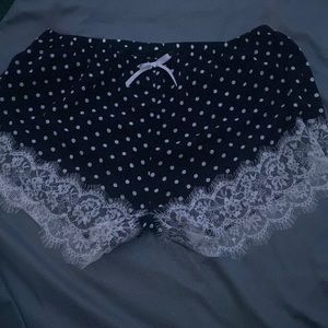 These are polka dotted black pajama shorts with lace at the thigh